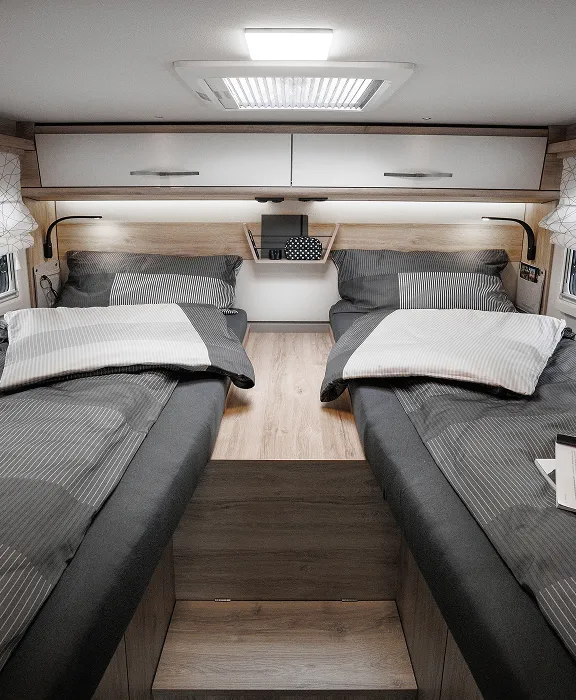 Wohnmobil fährt auf einer einsamen Straße durch eine weite, hügelige Wüstenlandschaft unter klarem blauem Himmel.